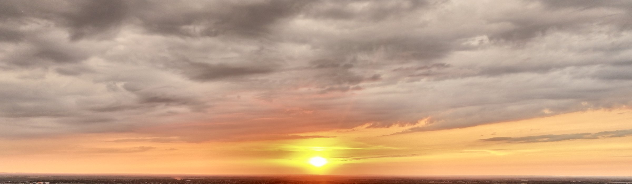 Golden evening sky above the Kansas City metro skyline of trees